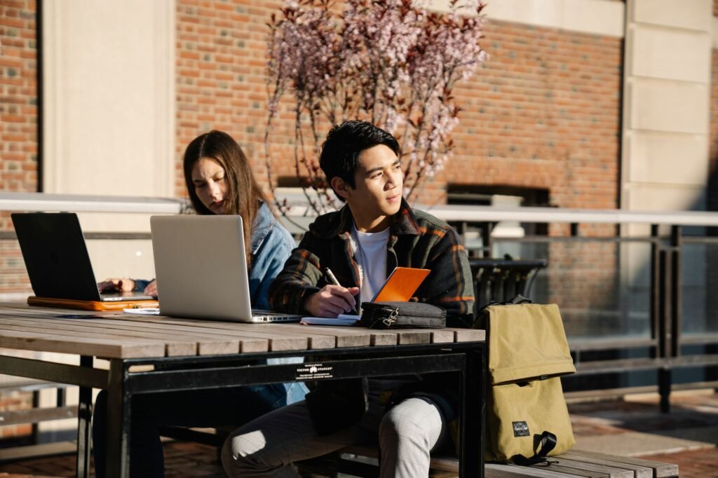A photo of a student studying with a car in the background, representing student discounts. — car insurance discounts Ne…